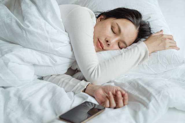 A person laying in bed, ready to go to sleep